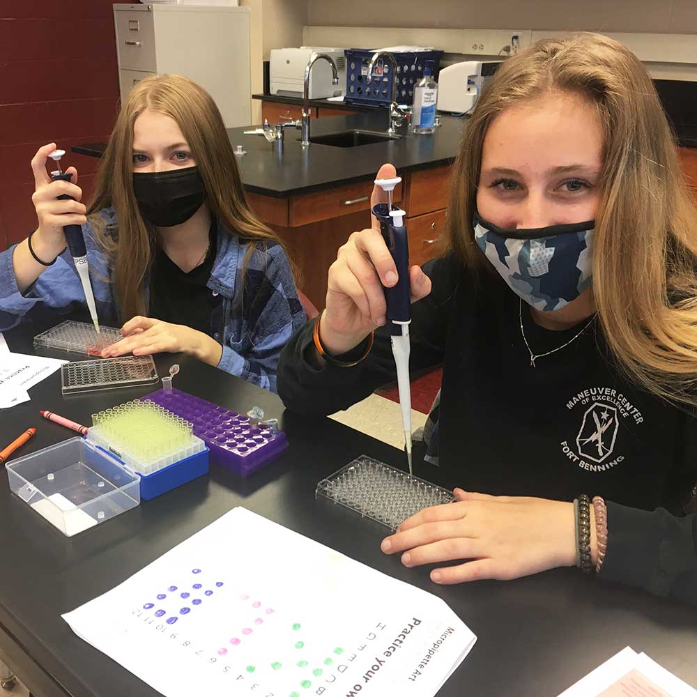 Two female students demonstrating their micropipetting skills.