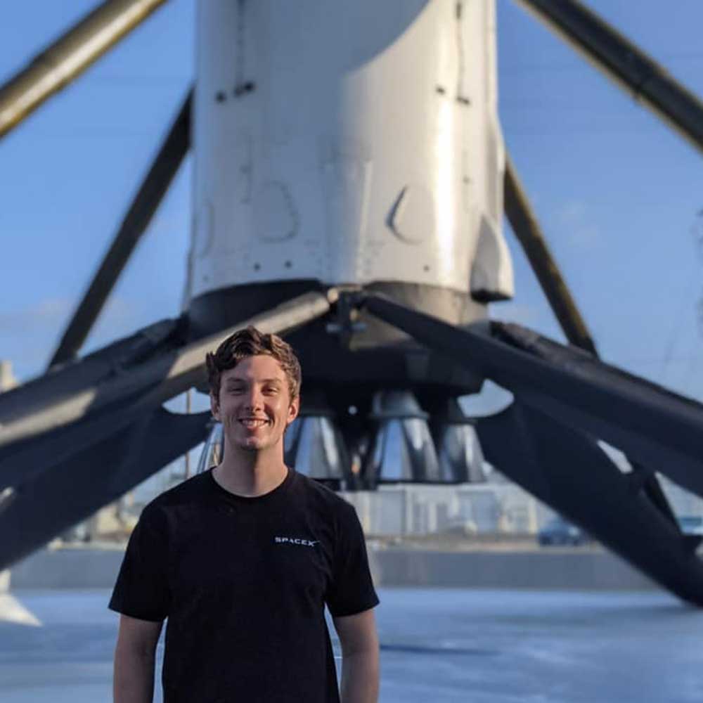 Former Centennial-X student standing in front of a SpaceX rocket.