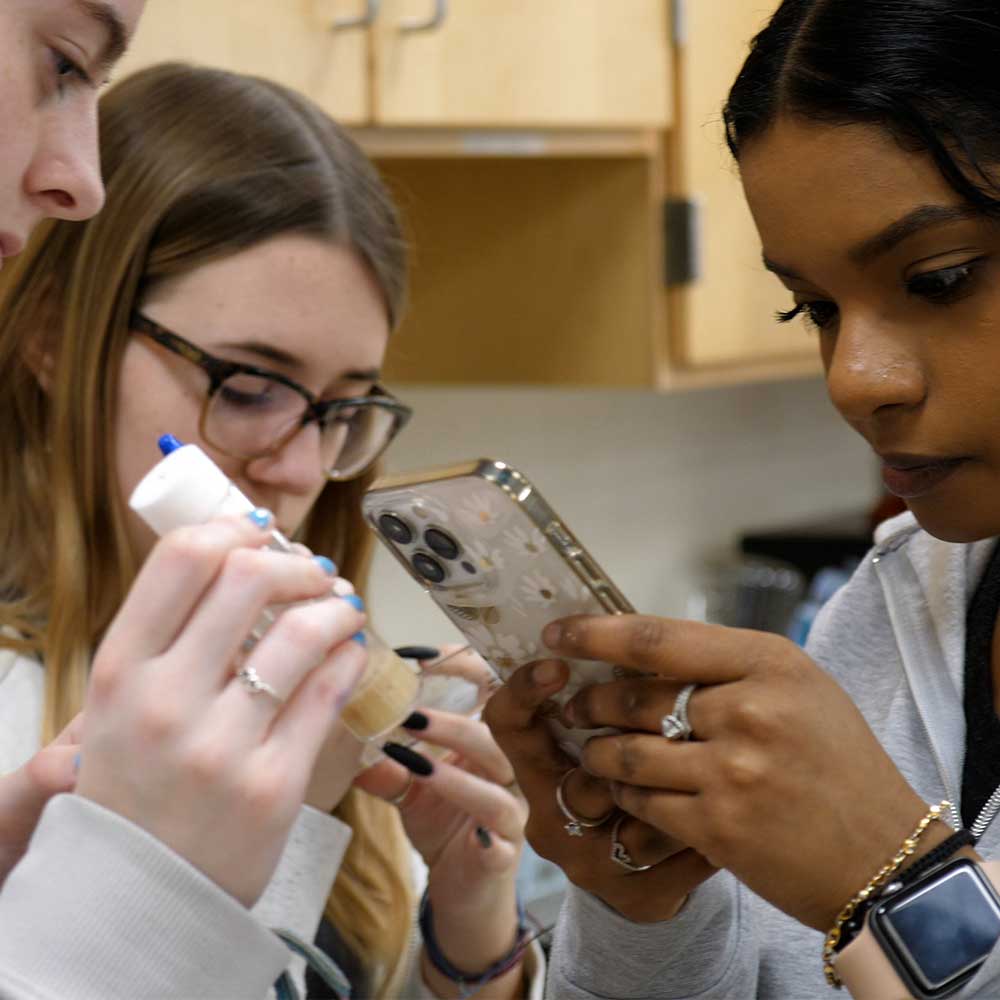 Three high school students conducting a fruit fly experiment.
